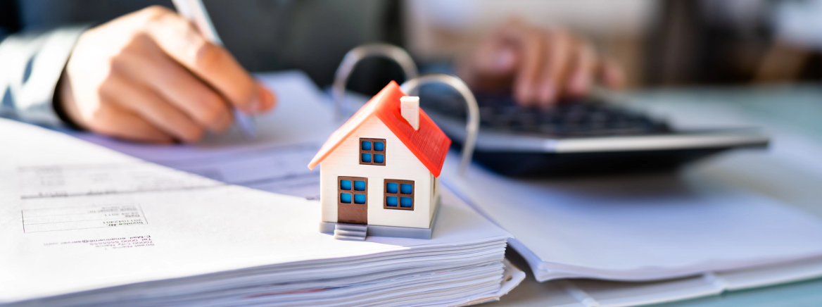 Header Image OTC Photo of individual calculating finances with a model house on the desk