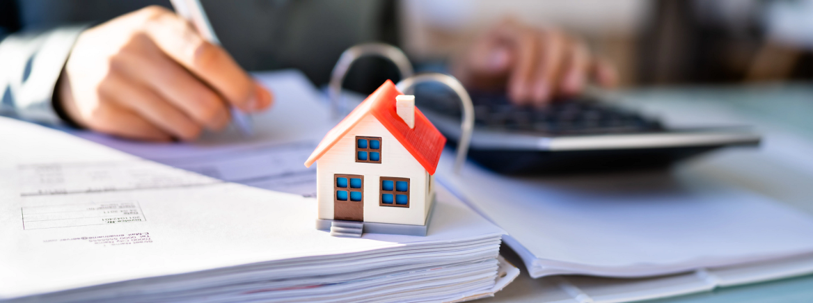 Photo of individual calculating finances with a model house on the desk