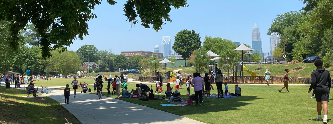 Groups of people walking or sitting in Independence Park in Charlotte.