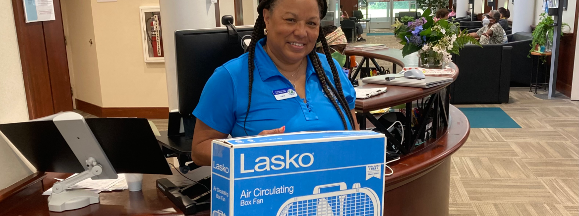 A Mecklenburg County employee holds a box fan in a cardboard box.