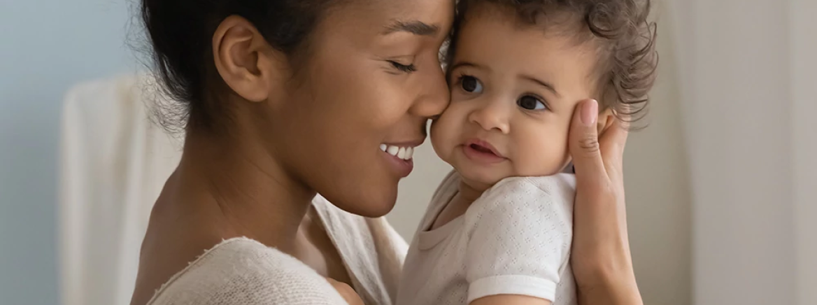 Happy young African American mom hold in hands hug cute little ethnic baby toddler show love care. Smiling biracial mother embrace cuddle small newborn infant child. Motherhood, childcare concept.