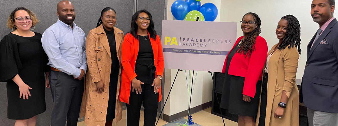 Peacekeepers Academy inaugural graduation Mecklenburg County Public Health Director Dr. Raynard Washington standing with graduates of the inaugural Peacekeepers Academy.