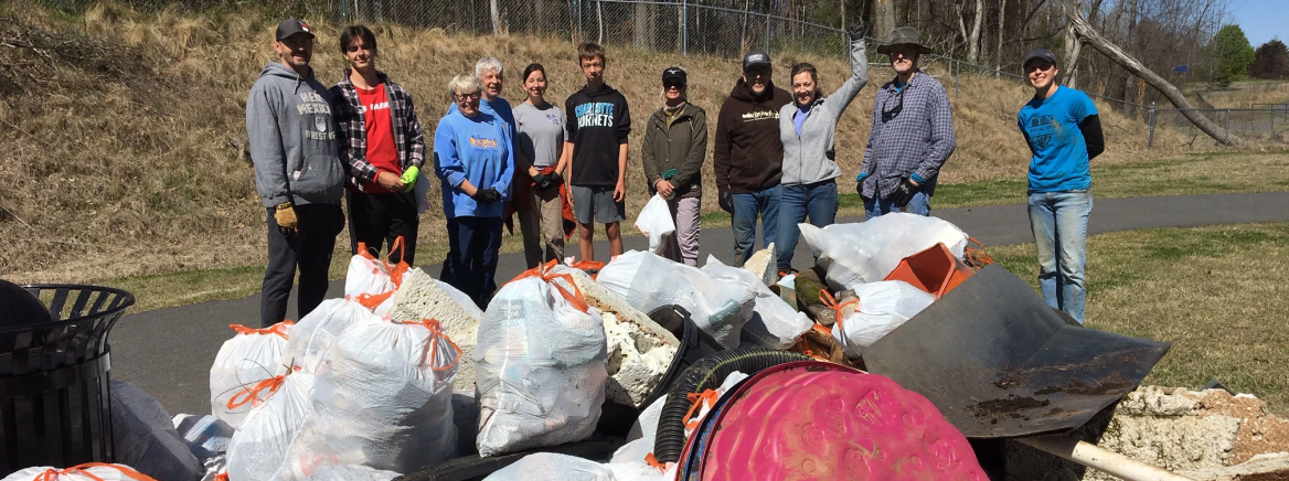 A group of volunteers standing behind bags of trash collected frrom a nearby creek during the Big Spring Clean.
