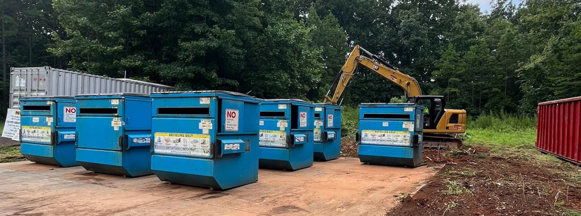 William R. Davie Self-Service Recycling Center Several blue recycling bins in front o construction equipment at the William R. Davie Recycling Center