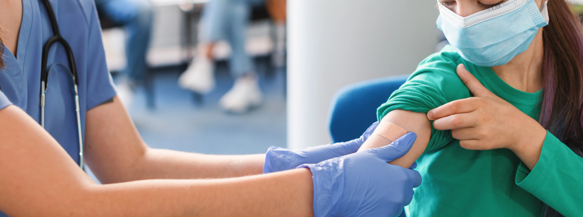 A nurse places a band aid on the arm of a female student following an immunization shot.