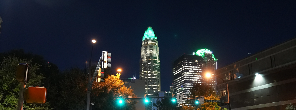 A view of uptown Charlotte at night with the buildings lit in green in honor of veterans.