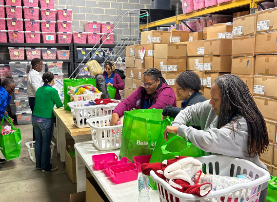 Three women at a table sorting through baby supplies and materials.