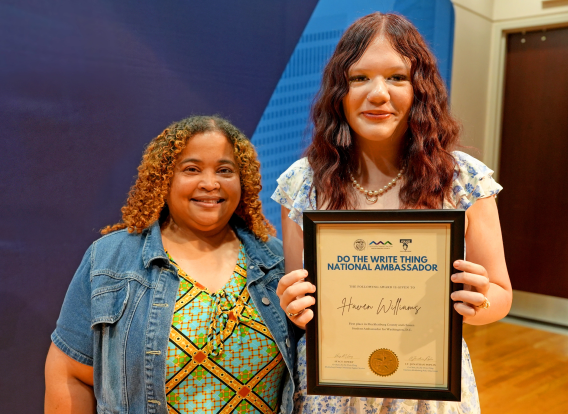 Haven Williams, a 7th grader at Northeast Middle, stands holding a plaque recognizing her selection as National Ambassador of Mecklenburg County’s annual “Do the Write Thing” writing contest.