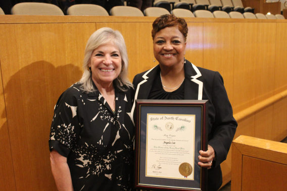 Left to right: County Manager Dena R. Diorio and Angela Lee in the CMGC Chamber. Lee is holding a plaque after being receiving the Order of the Long Leaf award.