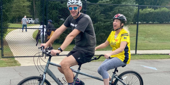 Two individuals riding an accessible bicycle.